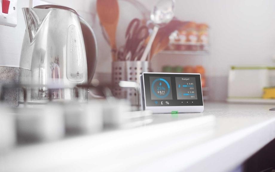 A smart meter sat atop a kitchen counter next to a silver kettle